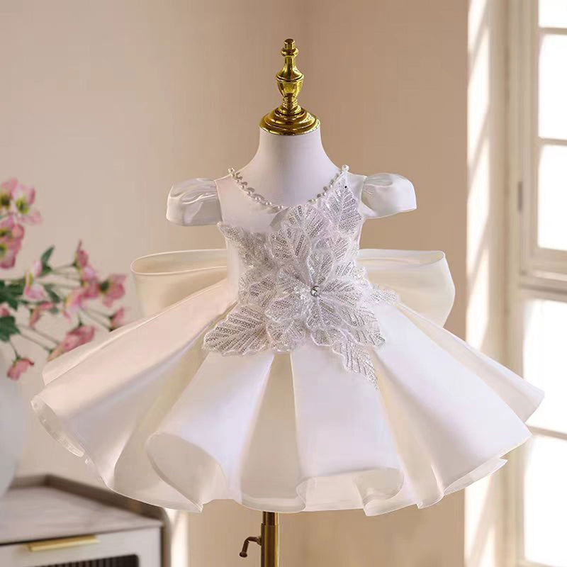 White satin flower girl dress with pearl details and bow for a formal wedding