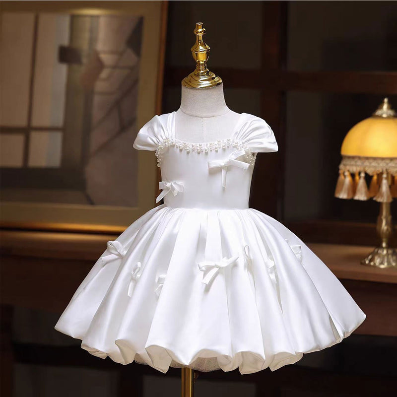 White knee-length flower girl dress with bow and pearl details for first communion