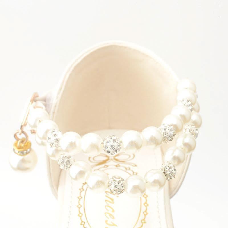 Detail of girls' white pearl ankle strap shoes
